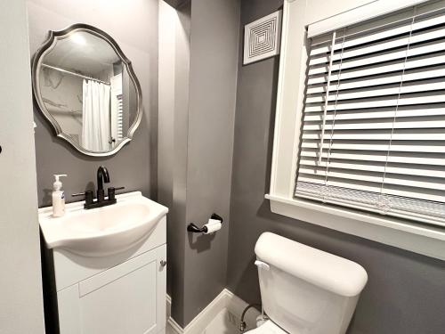 Baño blanco con lavabo y espejo en Vibrant City Home 4BD 2BA, en Brockton