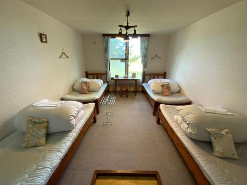 een kamer met drie banken en een tafel met een raam bij Mashuko Youth Hostel in Teshikaga