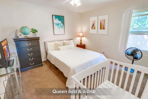 a white bedroom with a bed and a crib at Entire Private 3-Bedroom Home with Baby Crib, Wi-Fi & Laundry in San Diego