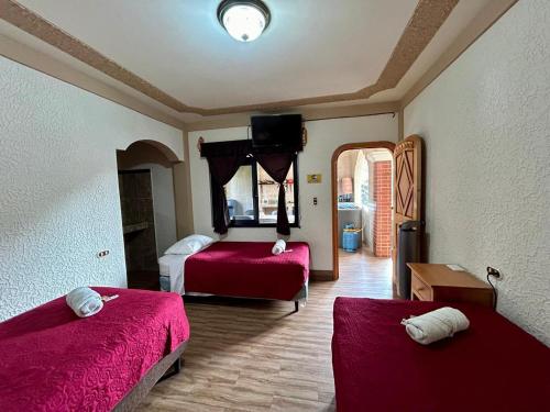a bedroom with two beds with red sheets and a chair at Posada don Miguel in Panajachel