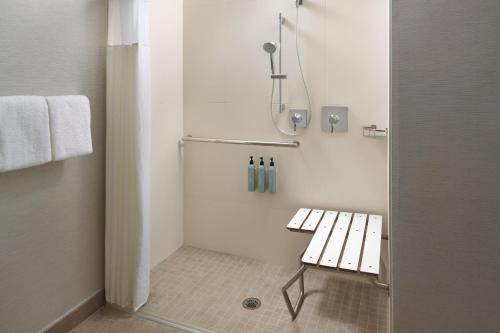 La salle de bains est pourvue d'une douche avec un banc. dans l'établissement Courtyard by Marriott Charlottesville, à Charlottesville