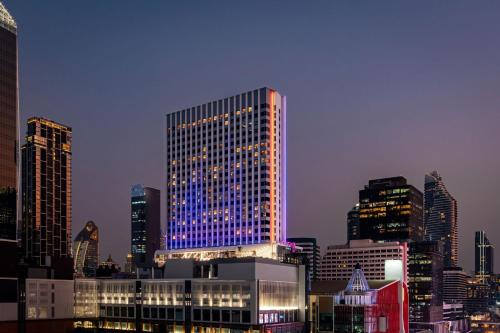 曼谷的住宿－曼谷拉差阿帕森购物区 MOXY 酒店，一座高大的建筑,上面有蓝色的灯光