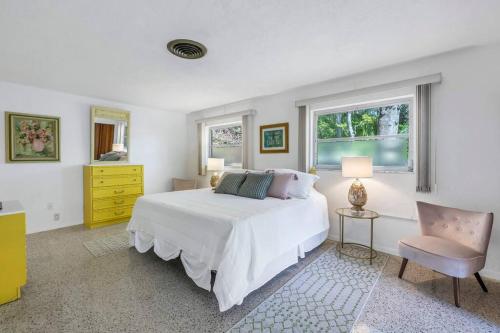 a white bedroom with a bed and a chair at Rainbow River Estate on Blue Run in Dunnellon
