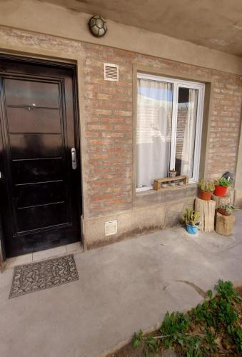 a house with a black door and a window at Departamento Chos Malal in Chos Malal