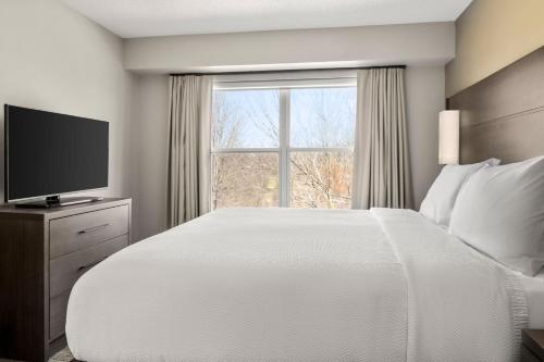 Un dormitorio con una gran cama blanca y una ventana en Residence Inn by Marriott Davenport, en Davenport