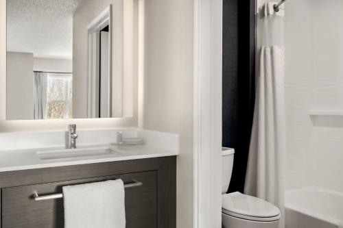 a bathroom with a sink and a toilet and a mirror at Residence Inn by Marriott Davenport in Davenport