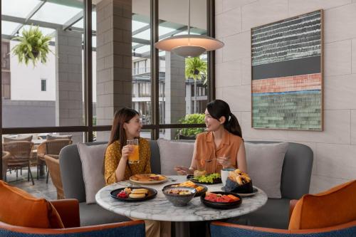 deux femmes assises à une table en train de manger dans l'établissement Courtyard by Marriott Bangkok Sukhumvit 20, à Bangkok