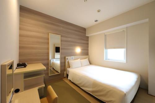 Smile Hotel Osaka Tennoji في أوساكا: غرفة في الفندق مع سرير ومكتب وسرير sidx sidx sidx