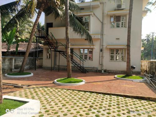 a building with two palm trees in front of it at His Grace Holiday Home - Nr to Malpe Beach in Udupi