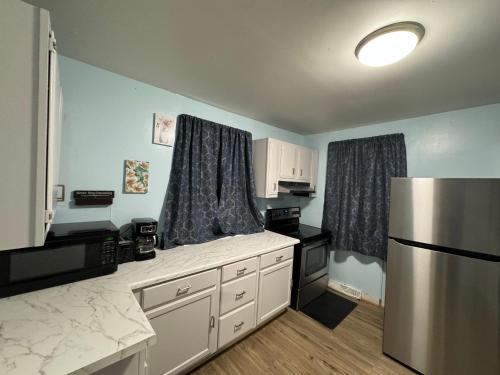 a kitchen with white cabinets and a refrigerator at Comfy Getaway, 5 Bed, Sleeps 9, walk to falls! in Niagara Falls