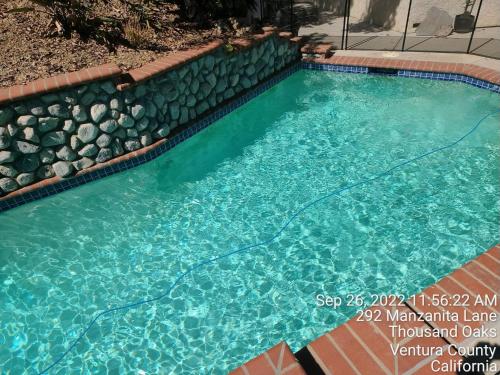 a swimming pool with a rock retaining wall and a swimming pool at NEW Modern apt w/pool & hot tub in nature in Thousand Oaks