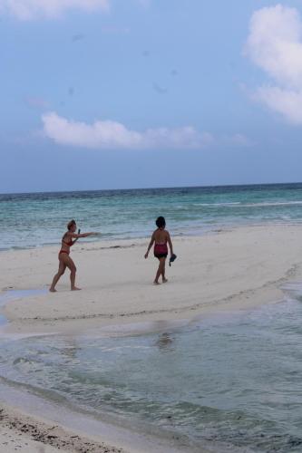 two women playing with a frisbee on the beach at Finimas Residence in Thimarafushi