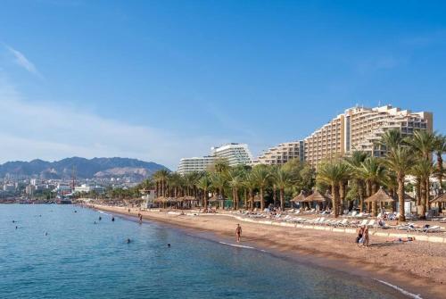 a beach with palm trees and people in the water at Red Sea Icon in Eilat