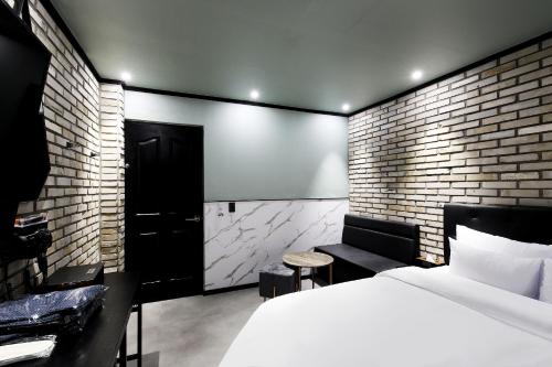 Stay 25 Hotel في سول: غرفة نوم بسرير وجدار من الطوب