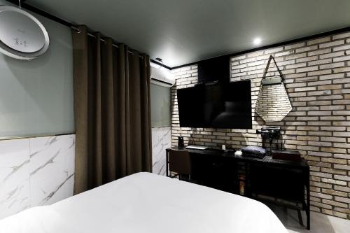 首爾的住宿－Stay 25 Hotel，卧室配有1张床和1台砖墙电视