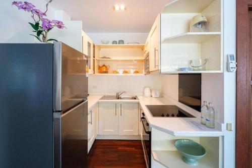 a kitchen with white cabinets and a stainless steel refrigerator at Kamala Beach Estate Resort - SHA Extra Plus in Kamala Beach
