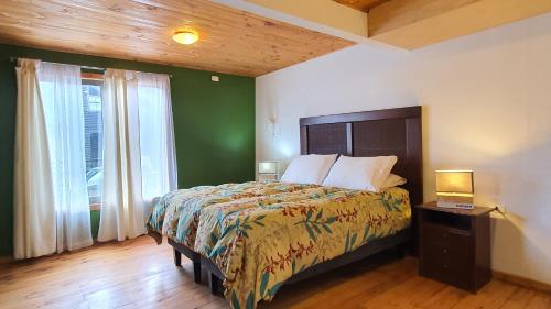 1 dormitorio con cama y pared verde en Cabañas Punta de Lobos en Pichilemu