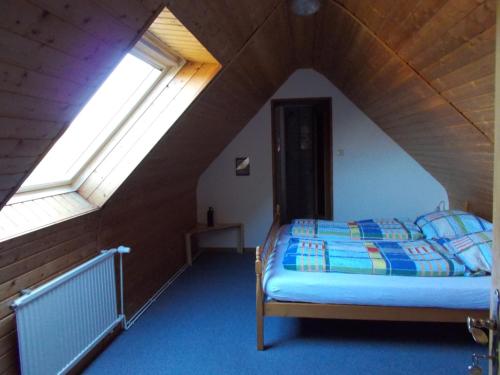 a bedroom with a bed in a attic with two windows at Pension Kraus in Esens