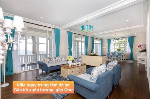 Elle comprend un salon doté d'un mobilier bleu et de rideaux bleus. dans l'établissement Villa Hạng Sang Đà Lạt - Gần Hồ Xuân Hương Gần Chợ Đà Lạt, à Xuan An
