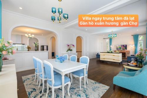 une salle à manger et une cuisine avec une table blanche et des chaises bleues dans l'établissement Villa Hạng Sang Đà Lạt - Gần Hồ Xuân Hương Gần Chợ Đà Lạt, à Xuan An