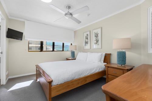 a white bedroom with a bed and a table at Pacific Beach Resort in Mooloolaba