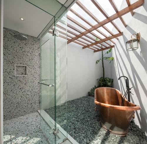 een badkamer met een koperen bad en een glazen douche bij Gria Kerten in Solo