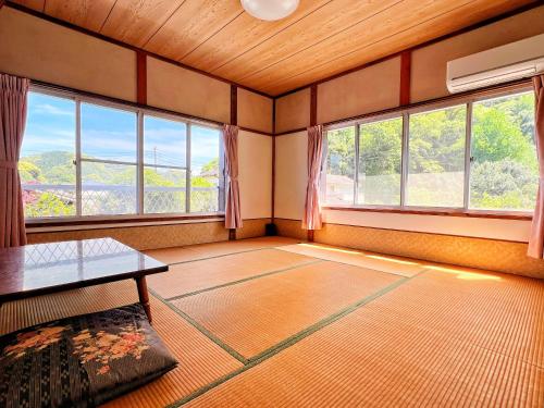een woonkamer met ramen en een tafel in een kamer bij Iriyama-So in Shimoda