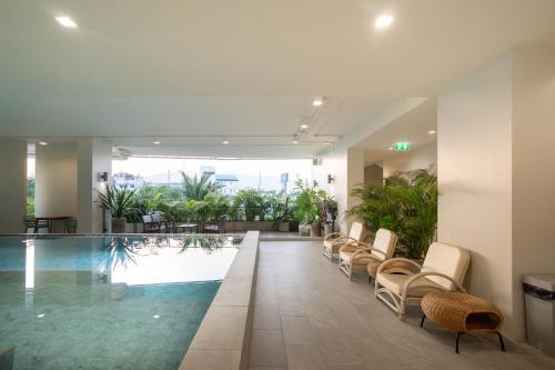 a hotel lobby with a pool and chairs at The Rise Suites Hotel, Chiang Mai - SHA Extra Plus in Chiang Mai
