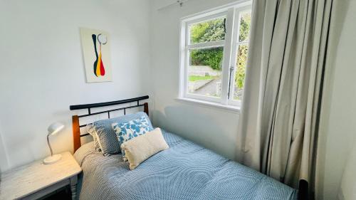 a small bedroom with a bed and a window at Stay on Glanmire in Wellington
