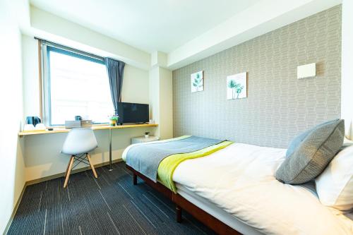 sypialnia z łóżkiem, biurkiem i oknem w obiekcie JA Hotel Bentencho 弁天町 w Osace