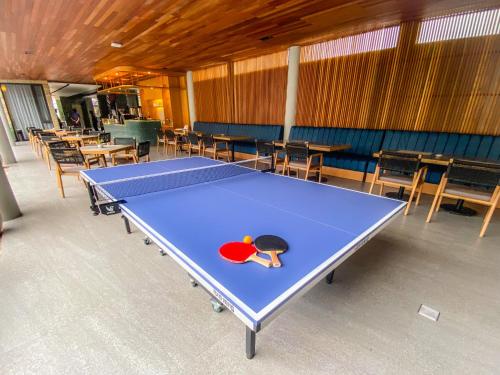 a ping pong table in a room with tables and chairs at Facade Hotel by Azana in Tawangmangu