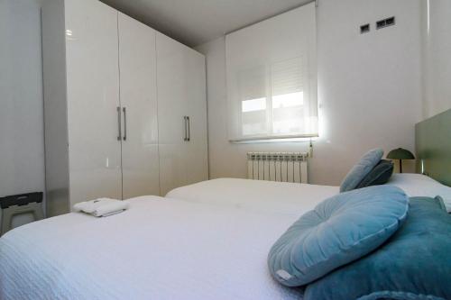 a white bedroom with two beds and a window at Alojamiento La Caseta de Nando in Tortosa