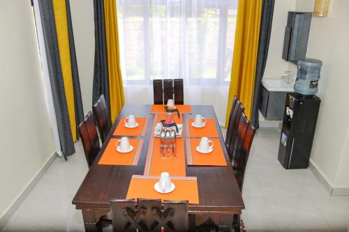 ein Esszimmer mit einem langen Tisch und orangefarbenen Servietten in der Unterkunft Hosted by Noel in Naivasha