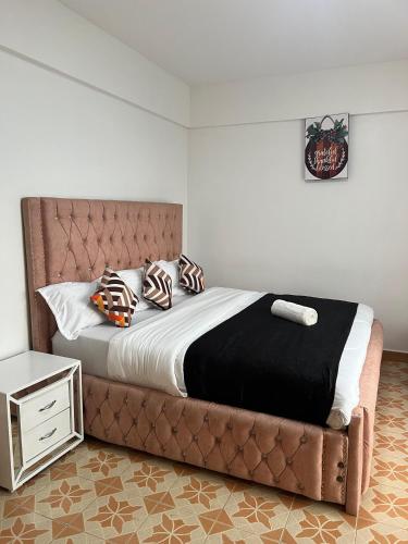 a bed with a leather headboard and pillows on it at Silva-Mindvalley in Nakuru