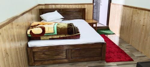 1 dormitorio con 1 cama con marco de madera en Menchugang homestay, en Gyalzing