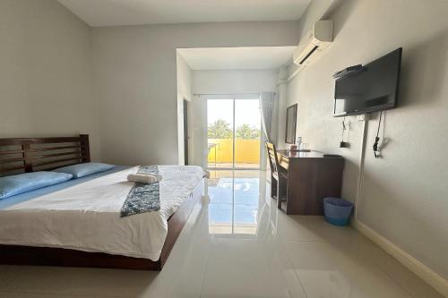 a bedroom with a bed and a sink and a television at Tara Apartment in Surat Thani