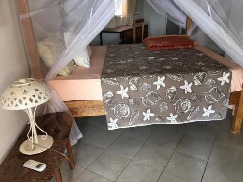 una camera con letto e tavolo con lampada di la villa sur la plage a Palmarin