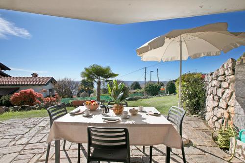 a table with chairs and an umbrella on a patio at Il Poggio Radioso Lake View & Garden - Happy Rentals in Nebbiuno