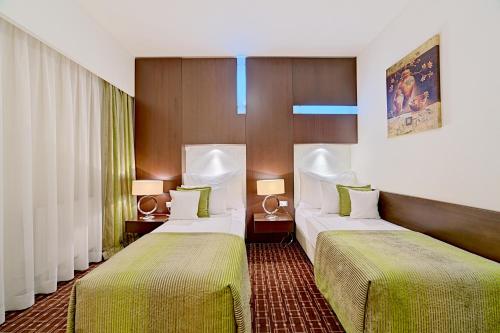 Habitación de hotel con 2 camas con sábanas verdes en Hotel Cubix, en Brasov