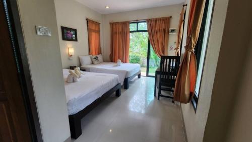 a bedroom with two beds and a window at Baan Klong Resort in Damnoen Saduak