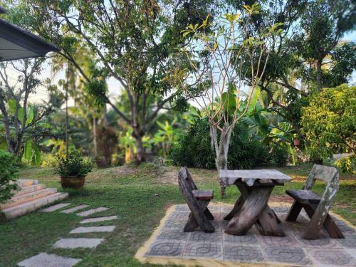 a picnic table and two benches in a park at Baan Klong Resort in Damnoen Saduak