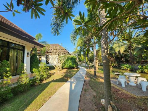 a row of white benches next to a house at Baan Klong Resort in Damnoen Saduak
