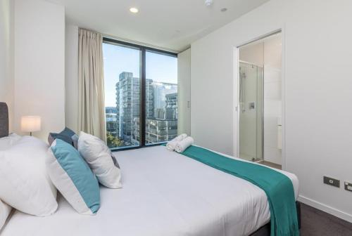 ein Schlafzimmer mit einem großen Bett und einem großen Fenster in der Unterkunft Gorgeous Seaview 2 Bedroom Apartment in Auckland CBD in Auckland