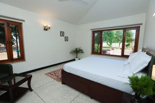 um quarto com uma cama grande e 2 janelas em De Vivendi Farm- A Rural Luxury Farmhouse Getaway em Bahora