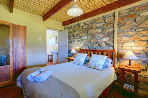 a bedroom with a large bed in a stone wall at Over The Mountain Guest Farm in George