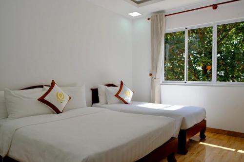 two beds in a white room with a window at Tan Son Nhat Con Dao Resort in Con Dao