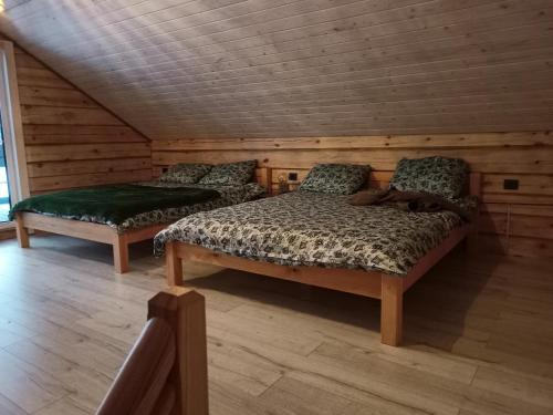 - une chambre avec 2 lits dans une pièce en bois dans l'établissement Sodyba vienkiemyje "Šeimos slėnis", à Kupiškis