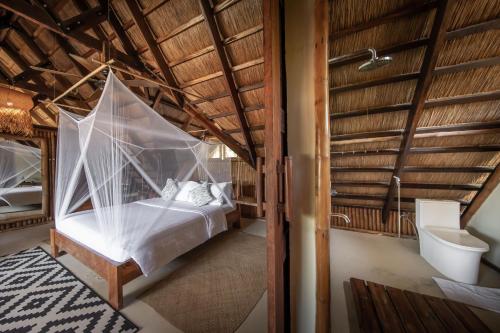 a bedroom with a bed with mosquito net at The Beach House Ocam Ocam in Busuanga