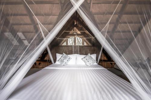 a bed in a room with a roof at The Beach House Ocam Ocam in Busuanga