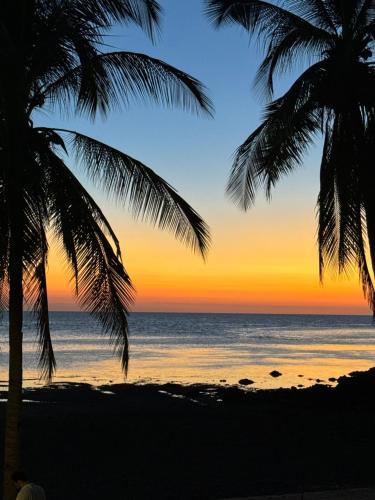 a sunset on the beach with palm trees at The Beach House Ocam Ocam in Busuanga